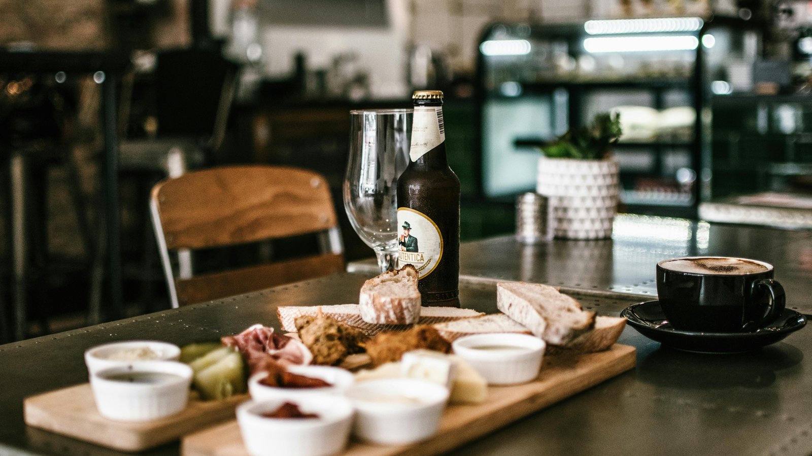 Elegant charcuterie and gourmet wings displayed on a rustic table with beer and football game playing.